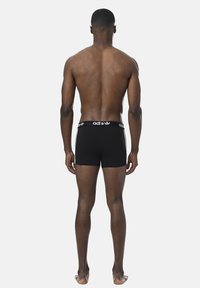 Schwarze Baumwoll-Boxershorts mit einem weißen Logo-Bund bieten eine enge Passform und werden von hinten gezeigt, wobei das minimalistische Design betont wird.