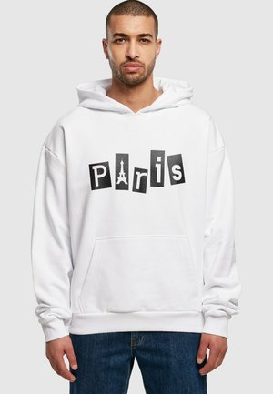 Hvid hoodie med et "Paris" grafisk motiv i sorte og hvide bogstaver, med Eiffeltårnets symbol integreret. Blødt stof med en lomme foran.