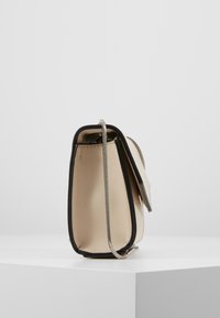 Borsa a mano beige in pelle con bordi neri, forma rettangolare verticale, tracolla a catena argento e chiusura a patta. Texture liscia, design minimalista.