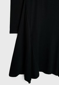 Musta, pitkähihainen mekko, jossa on virtaava siluetti ja epäsymmetrinen helma. Pehmeä, matta kangas, jossa on sileä pinta ja siistit ompeluyksityiskohdat.