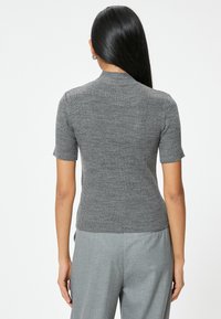 Kurzärmliger, gerippter Pullover in Dunkelgrau mit einer taillierten Silhouette und hohem Halsausschnitt. Strukturierter Strickstoff mit dezenten Details.