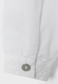 Polsino di camicia bianco con ricami decorativi e un bottone in tonalità argentata con design floreale. Tessuto liscio e texture arricciata.