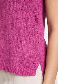 Haut sans manches en maille rose vif avec un tissage lâche, des fentes latérales et un ourlet côtelé. Tissu texturé avec une coupe décontractée.