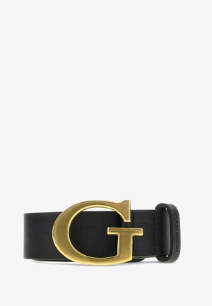 Cintura in pelle nera con grande fibbia dorata a forma di lettera G e passante nero con rilievo '"GUESS JEANS"' su sfondo bianco.
