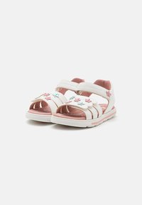 Valkoiset sandaalit pinkeillä yksityiskohdilla, joissa on tarranauhat, avoimet varpaat ja koristeelliset tähtisovitteet pinkissä ja sinisessä yläosassa.