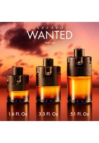 Tre størrelser af Azzaro Wanted parfume flasker med ravfarvet væske og sorte hætte vist mod en solnedgangsbaggrund med flaskevolumener nedenfor.