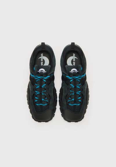 Black athletic shoes with textured mesh and suede materials. Features blue laces, padded collar, and rubber soles with traction patterns.