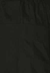 Tela negra con una textura mate, que presenta una costura horizontal y un detalle de cintura fruncida. Sin patrones ni adornos adicionales.