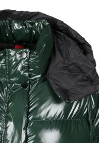 Błyszcząca ciemnozielona kurtka puchowa z wysokim kołnierzem, czarnymi zatrzaskami i odpinanym czarnym kapturem zapinanym na guziki.