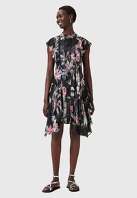 Kurzes, schwarzes Blumenkleid mit einem ausgestellt Rock, das pinke und grüne Muster, geschichteten Stoff und einen hohen Kragen aufweist.