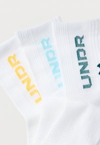 Άσπρες βαμβακερές κάλτσες με ριμπ μανσέτες, διακοσμημένες με το κείμενο «UNDR» κεντημένο σε κίτρινο, ανοιχτό μπλε και σκούρο τιρκουάζ χρώμα. Υφασμάτινο μοτίβο με υφή.