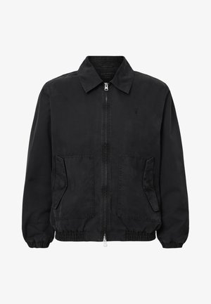 Chaqueta negra con cremallera frontal, cuello extendido, dos bolsillos frontales y puños elásticos. Fabricada con una tela suave y de corte relajado.