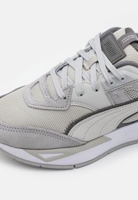 Szare sportowe sneakersy z siateczki i zamszu, o okrągłym kształcie, teksturowanej powierzchni i wyraźnym logo na języku.