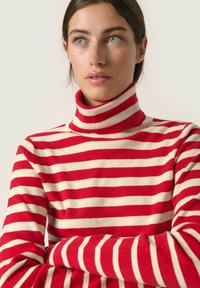 Rdeče in kremne proge turtleneck pulover iz mehkega blaga, ki ima tesnjen dizajn z dolgimi rokavi in visokim ovratnikom.