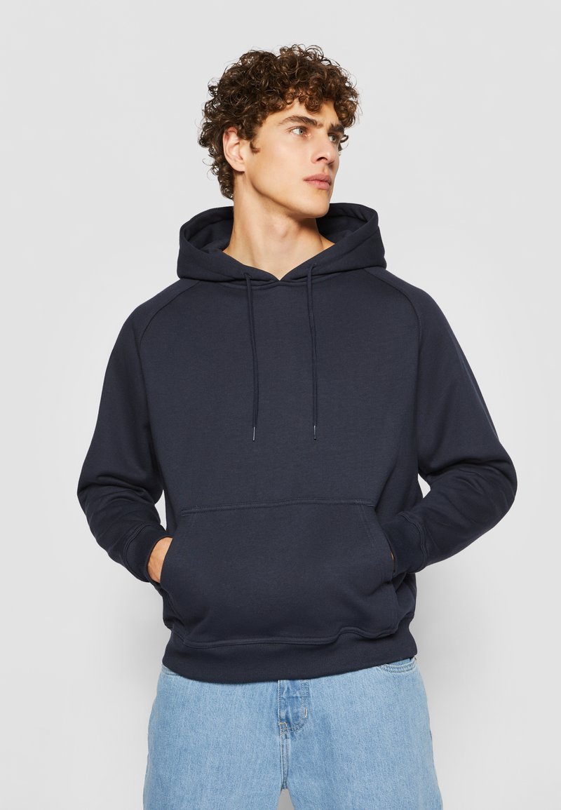 Felpa blu navy realizzata in tessuto morbido, con tasca frontale, cappuccio regolabile con cordino e polsini e orlo a costine.