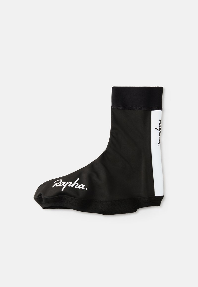 Cubierta de zapato de ciclismo negra hecha de tela elástica con una parte superior acanalada. Presenta acentos blancos y el logo "Rapha." en el lateral.