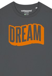 Graues T-Shirt mit einem orangefarbenen "DREAM"-Grafik in einer fetten, stilisierten Schriftart in der Mitte. Glatte Stofftextur. Runder Halsausschnitt.