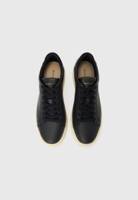 Schwarze Ledersneaker mit runder Form, flachen Schnürsenkeln, einer weichen, hellbraunen Innensohle und einer hellen Gummisohle. Mit goldener Markenkennzeichnung ausgestattet.