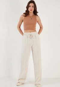 Lichtbeige sweatpants met een trekkoord in de taille, zijnaad en een ontspannen pasvorm, gecombineerd met een aansluitend bruin geribbeld crop top.
