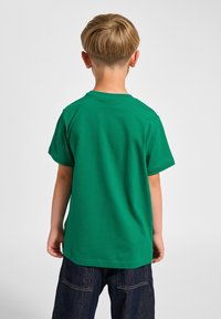 Grön kortärmad t-shirt i bomull, med rund hals och enfärgad design. Tyget verkar slätt med en avslappnad passform.