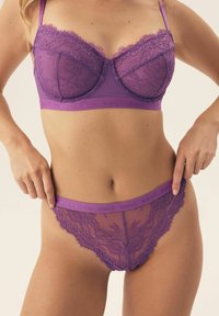 Fioletowy komplet koronkowej bielizny, składający się z balkonetki i pasujących majtek bikini, z kwiatowymi wzorami i miękkimi elastycznymi paskami.