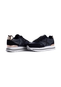 Schwarze Sport Sneakers aus einer Kombination von Leder und Wildleder, ausgestattet mit einem metallisch goldenen Akzent an der Ferse und einer weißen Gummisohle.