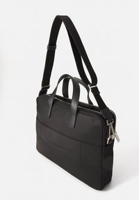 Bolso mensajero de textil negro con detalles en cuero, doble asa superior, correa de hombro ajustable y cierre de cremallera. Textura suave y diseño minimalista.