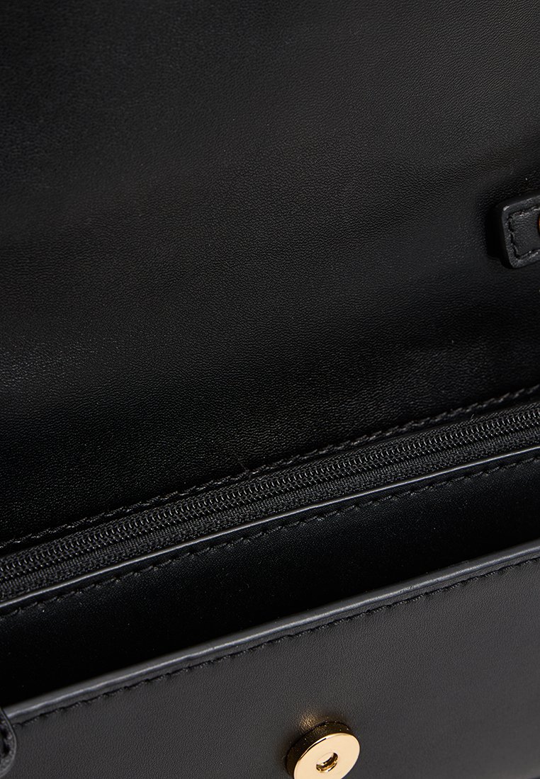 Czarna skórzana torebka wnętrze z zamkniętą kieszenią i złotym zatrzaskiem. Gładka faktura bez widocznych wzorów.