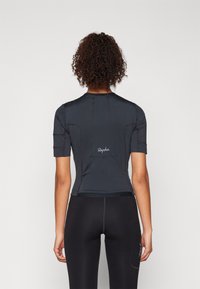 Korte ermet sykkeltrøye i svart, med et tettsittende design, elastisk stoff og en baklomme. Har "Rapha"-logoen i hvitt.