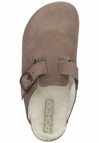 Zapatilla de ante marrón con dos correas ajustables, punta redonda y forro de felpa. Cuenta con una suela texturizada y un logotipo en la plantilla.