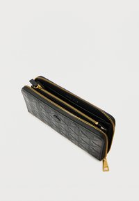 Mustast tikandiga rahakott kuldse tõmblukuga, millel on mitu sektsiooni ja tekstureeritud välimus. Tõmbluku tõmblikul on väike metallist silt.