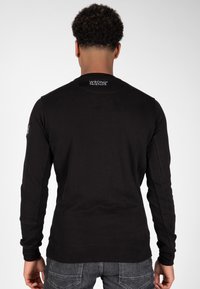 Felpa nera a maniche lunghe con polsini e orlo a coste. Presenta un logo sulla parte posteriore del collo e un logo accentato sulla manica sinistra. Materiale in misto cotone.