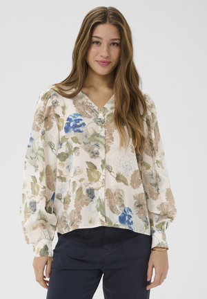 Lilleline pluus V-kaeluse ja nööbiga, tekstuurse kreemika, rohelise ja sinise tooniga kangaga. Pikkade, puhvvarrukatega.