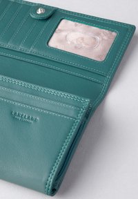 Teal leather wallet with multiple card slots, a clear ID window, and a zippered compartment. Features subtle stitching and branding.