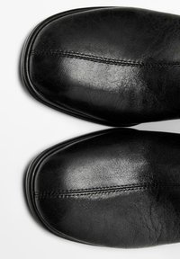 Black leather shoes with a rounded toe, smooth texture, and a subtle seam detail across the top. Sole is slightly contoured.