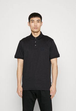 Polo shirt noir en coton avec un col classique, une patte de boutonnage à trois boutons et un petit logo sur la poitrine gauche. Manches courtes.