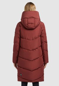 Cappotto imbottito rosso con cappuccio, caratterizzato da un design trapuntato a forma di chevron, maniche lunghe e una toppa con logo visibile vicino all'orlo.