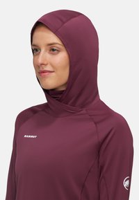 Bordeauxfarbener Hoodie mit einer angepassten Kapuze, langen Ärmeln und flachen Nähten. Verfügt über ein Logo auf der Brust und ein rundes Logo am Sleeve.
