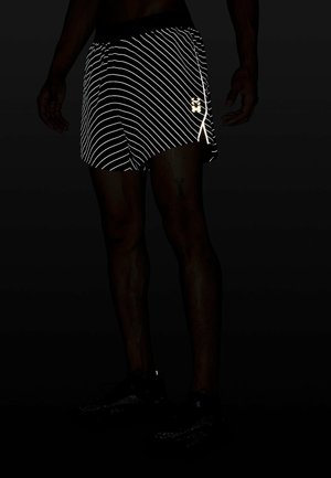 Black athletic shorts with reflective white diagonal stripes, featuring a logo on the lower right side and an elastic waistband.