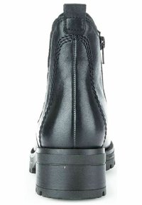 Bottine en cuir noir avec une surface texturée, coutures droites, une fermeture éclair sur le côté et une semelle en caoutchouc épaisse.
