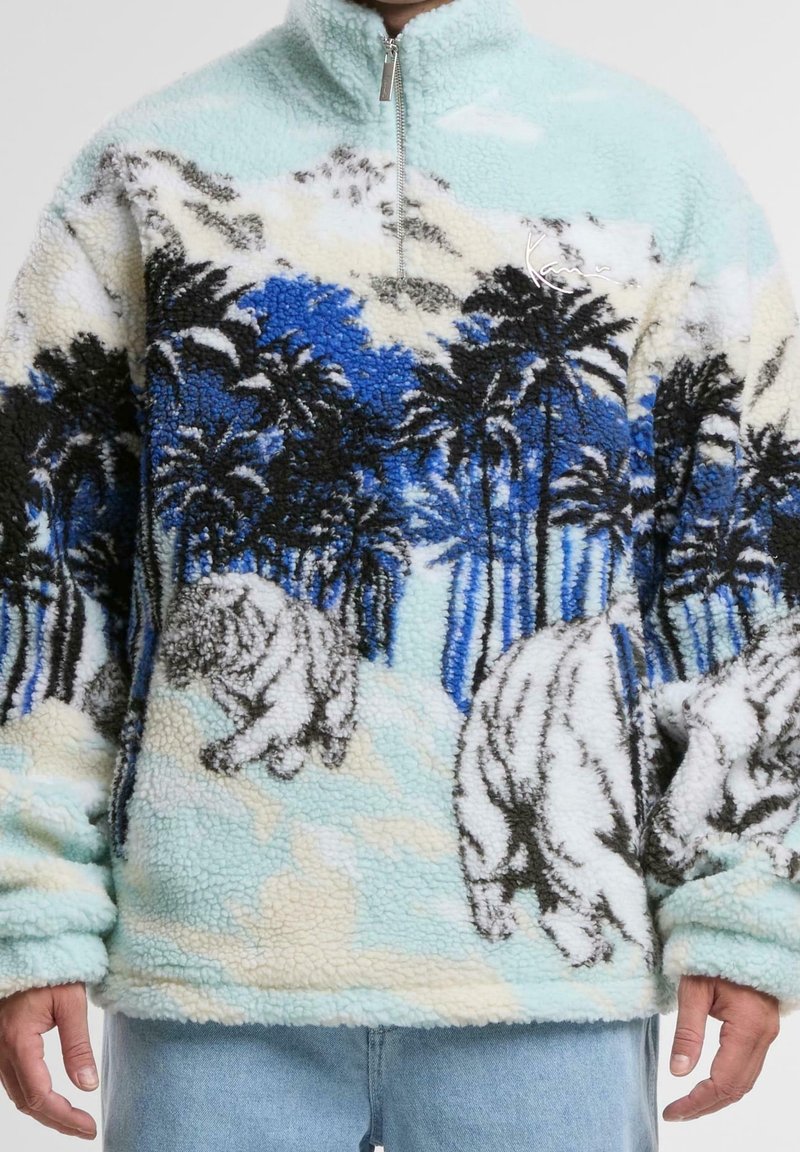 Fleece pullover featuring a light blue and white palm tree pattern, with black and blue accents and polar bear illustrations. Half-zip closure.