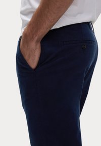 Navyblauwe broek van katoen, met een zijzak en een knoopzak aan de achterkant. Glad materiaal met een getailleerde pasvorm.