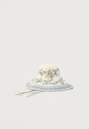 Florlet solhat med bred skygge i cremefarvet med blå mønstre, med mønstret kant og snore bagpå for sikker pasform. Fremstillet i bomuld.