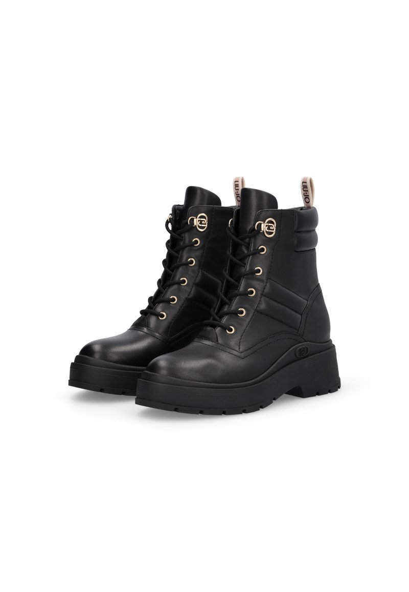 Botas de tobillo de cuero negro con cordones, ojales dorados, cuello acolchado y suela de goma gruesa. Cuenta con una etiqueta con el logo en el talón trasero.
