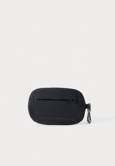 Μαύρο τσαντάκι με φερμουάρ και ανάγλυφη υφή ριμπ, με μεταλλικό κλιπ και ανάγλυφο λογότυπο Emporio Armani στο μπροστινό μέρος, πάνω σε λευκό φόντο.