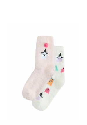Due calzini soffici, uno rosa con un fantasma che indossa un cappello nero e un pon pon rosa, l'altro bianco con fantasmi colorati che indossano cappelli neri.
