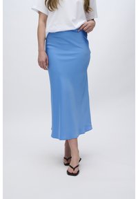 Lys blå, satin midi-nederdel med en glat tekstur, der har en elastisk talje og en svævende silhuet, parret med sorte flip-flops.