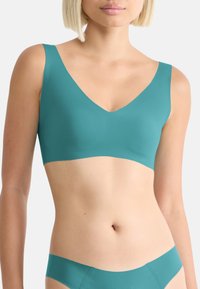Turquoise seamless bralette with wide straps and a V-neck design. Made from smooth fabric, featuring no visible fastenings or embellishments.
