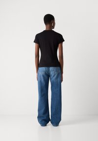 Black fitted t-shirt with short sleeves paired with loose, light blue denim jeans. The jeans feature visible back pockets and stitching.