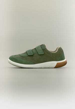 Zapatilla de ante verde con suela de goma blanca, que presenta dos correas ajustables y un detalle marrón en el borde de la suela.